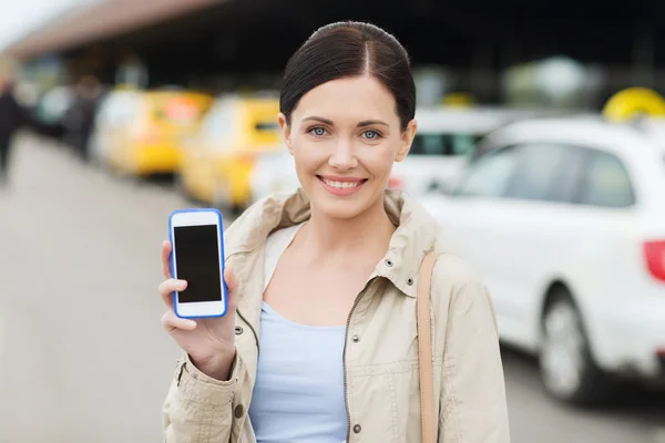 Mulher sorrindo mostrando smartphone sobre táxi na cidade — Fotografia de Stock