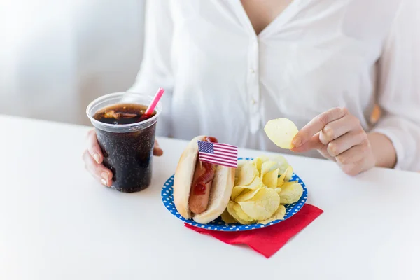 Närbild på kvinna äta chips, varmkorv och cola — Stockfoto