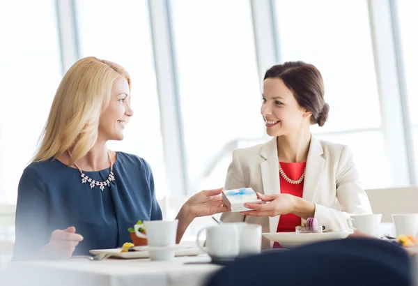 Happy women giving birthday present at restaurant — Stock Photo, Image