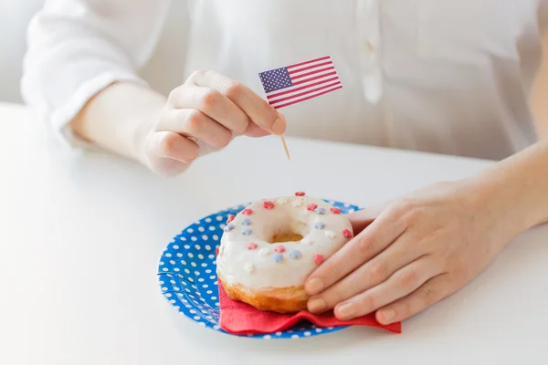 Female hands decorating donut with american flag — Stock Photo, Image