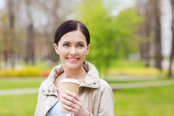 公園内のコーヒーを飲む女性の笑みを浮かべてください。 — ストック写真