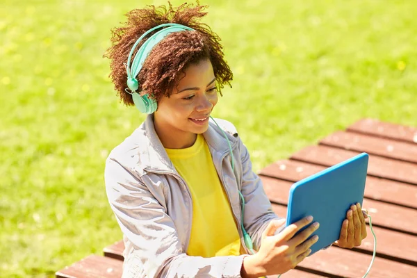 Glückliche Afrikanerin im Kopfhörer mit Tablet-PC — Stockfoto