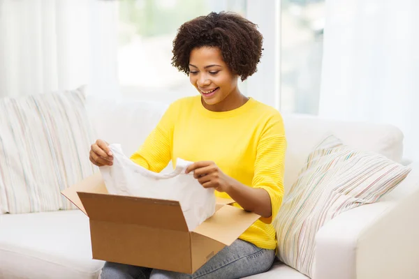 Mujer joven africana feliz con la caja del paquete en casa —  Fotos de Stock