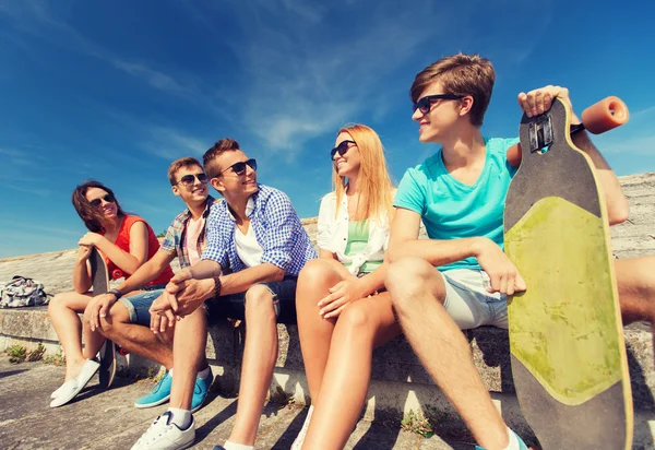 Group of smiling friends sitting on city street — Stock Photo, Image