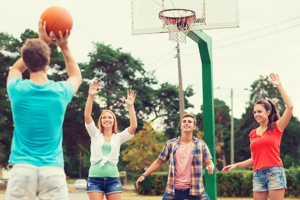 Skupina usměvavá teenagerů hrát basketbal — Stock fotografie