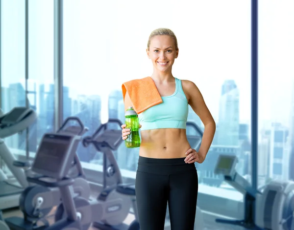 Happy woman with bottle of water and towel in gym — Stock Photo, Image
