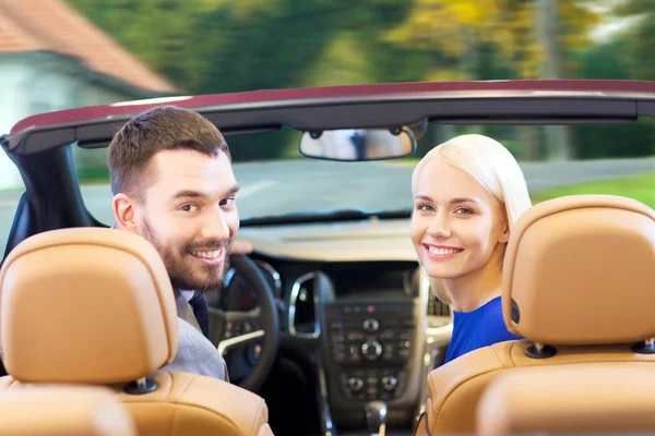 Happy couple driving in cabriolet car over city — Stock Photo, Image