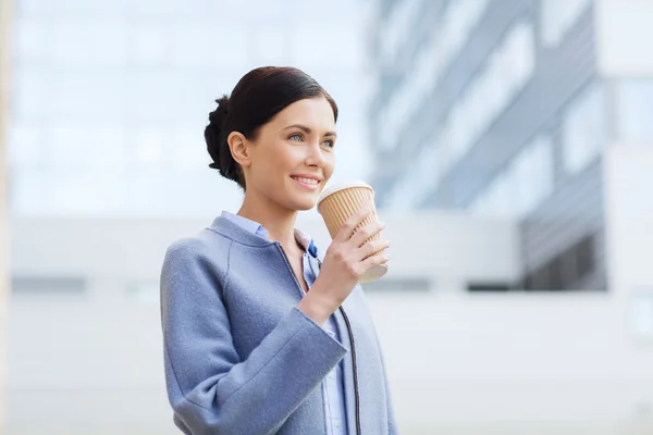 Usmívající se žena pití kávy v městě — Stock fotografie