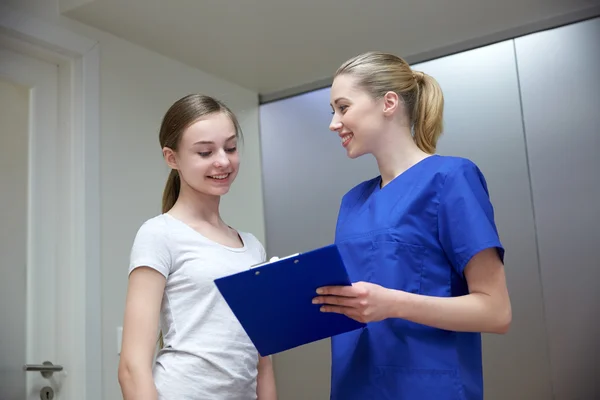 Smiling nurse with clipboard and girl at hospital — Stock Photo, Image