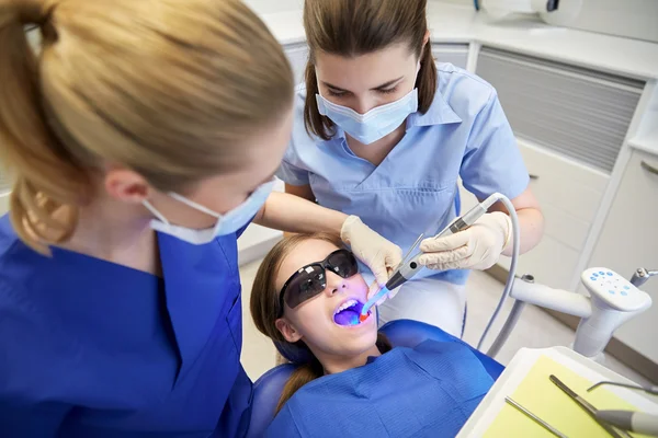 Dentistas mulheres que tratam os dentes da menina paciente — Fotografia de Stock