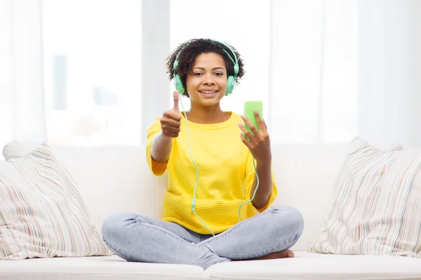 Mujer africana feliz con teléfono inteligente y auriculares —  Fotos de Stock