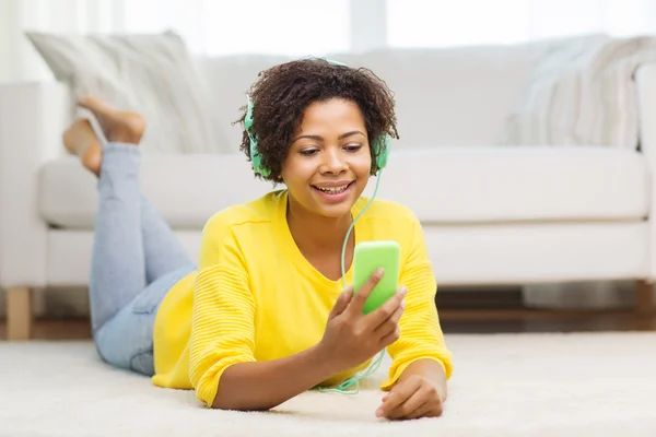 Mujer africana feliz con teléfono inteligente y auriculares —  Fotos de Stock