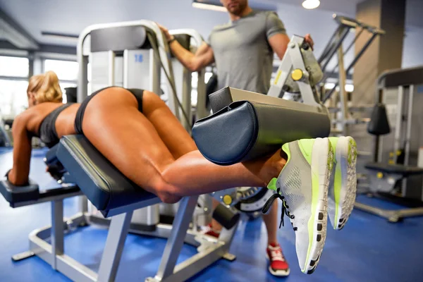 Homem e mulher flexionando músculos na máquina de ginásio — Fotografia de Stock