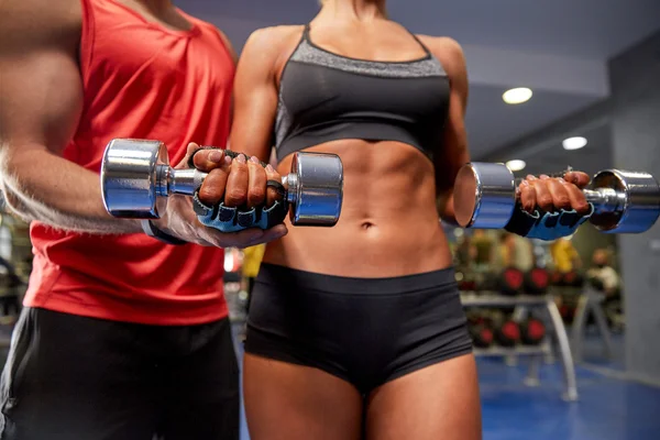 young couple with dumbbell flexing muscles in gym