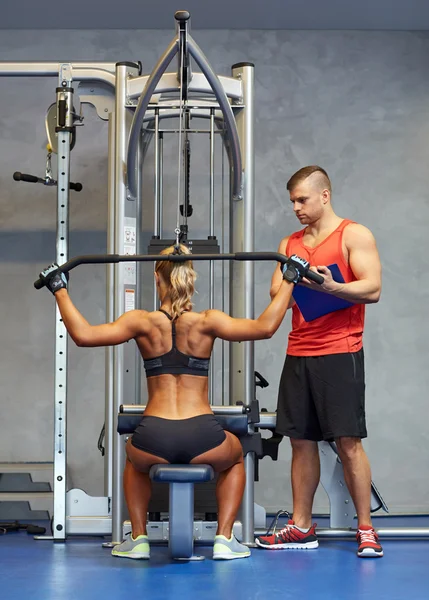 Hombres y mujeres flexionando los músculos en la máquina de gimnasio —  Fotos de Stock