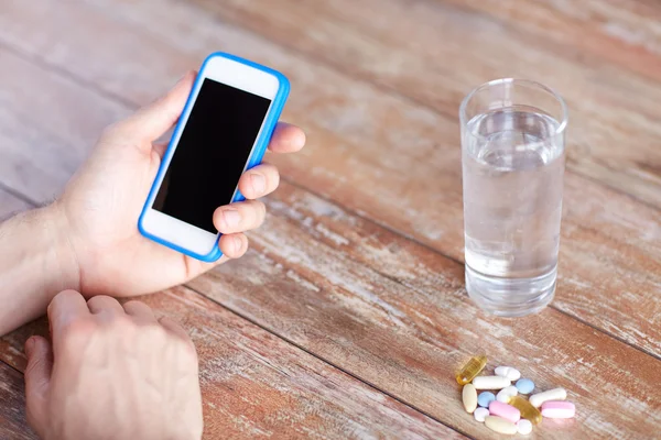 Primer plano de las manos con smartphone, pastillas y agua — Foto de Stock