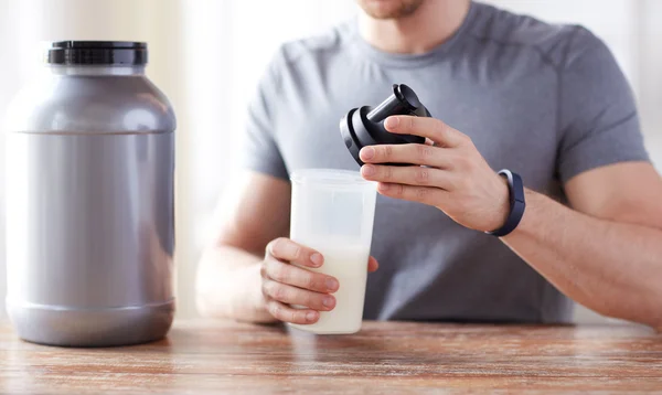 Primer plano del hombre con botella de batido de proteínas y frasco —  Fotos de Stock