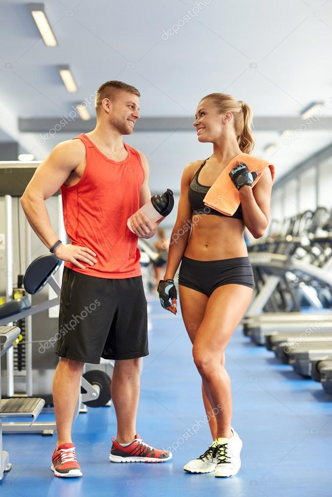 Smiling man and woman talking in gym Stock Photo by