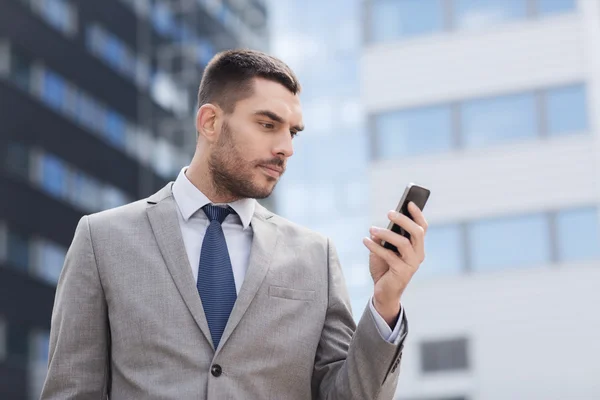 Serious businessman with smartphone outdoors — Stock Photo, Image