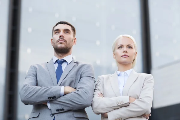 Hombres de negocios serios de pie sobre el edificio de oficinas — Foto de Stock