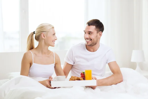 Счастливая пара завтракает в постели дома — стоковое фото