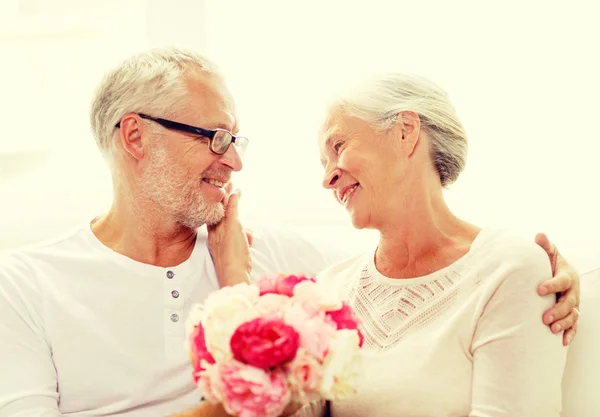 Felice coppia anziana con mazzo di fiori a casa — Foto Stock