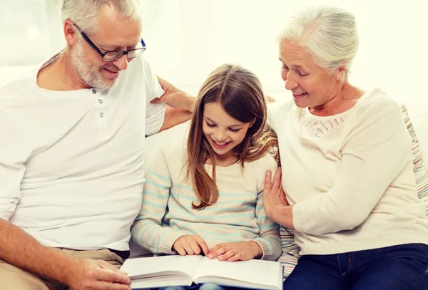 Família sorridente com livro em casa — Fotografia de Stock