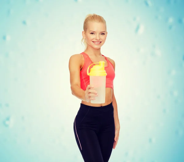 Smiling sporty woman with protein shake bottle — Stock Photo, Image