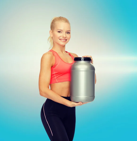 Mujer deportiva sonriente con tarro de proteína — Foto de Stock