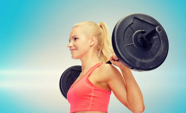 Sorrindo mulher desportiva exercitando com barbell — Fotografia de Stock