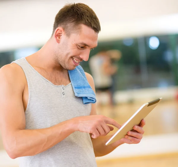 Hombre joven con tablet PC y toalla en el gimnasio — Foto de Stock