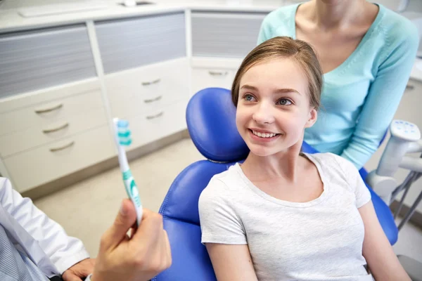 Happy tandläkare visar tandborste till tålmodiga Tjej — Stockfoto