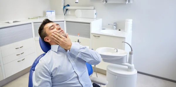 Hombre teniendo dolor de muelas y sentado en la silla dental —  Fotos de Stock