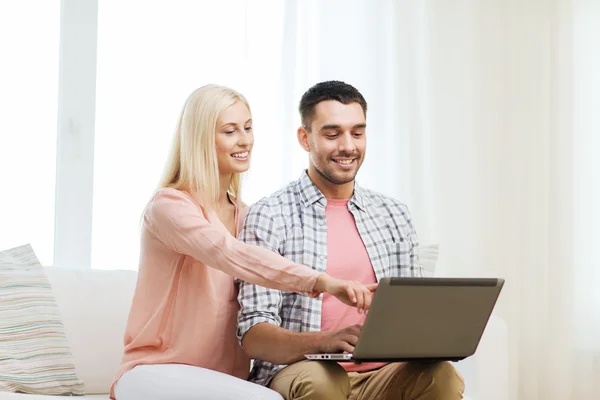 Sorrindo casal feliz com computador portátil em casa — Fotografia de Stock