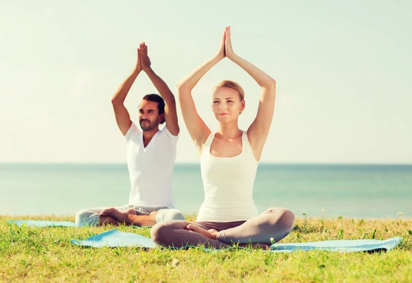 Lächelndes Paar macht Yoga-Übungen im Freien — Stockfoto