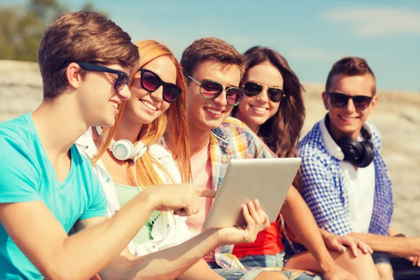 Groep lachende vrienden met tablet pc buitenshuis — Stockfoto