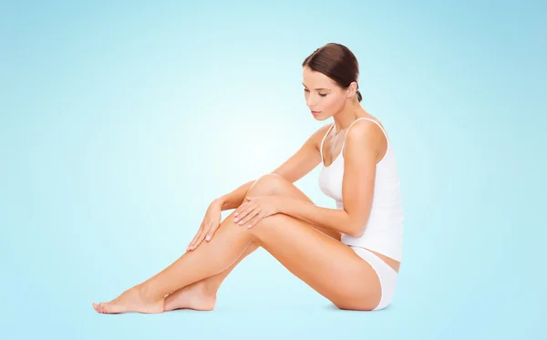 Beautiful woman in cotton underwear touching legs — Stock Photo, Image