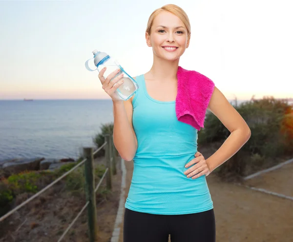 Happy woman with water bottle and towel outdoors — Stock Photo, Image