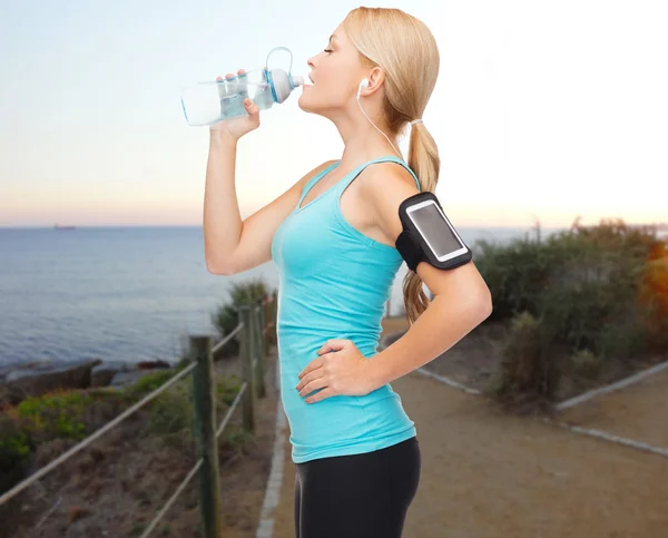 Mujer deportiva escuchando música y agua potable — Foto de Stock