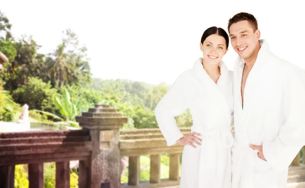 Happy couple in bathrobes over spa hotel resort — Stock Photo, Image