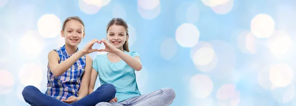 Happy little girls showing heart shape hand sign — Stock Photo, Image