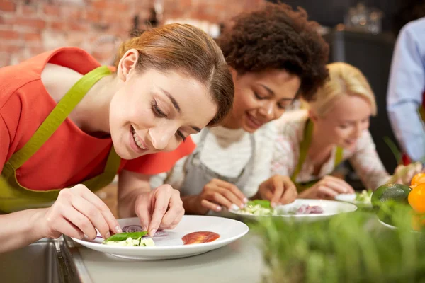 Mujeres felices cocinando y decorando platos — Foto de Stock