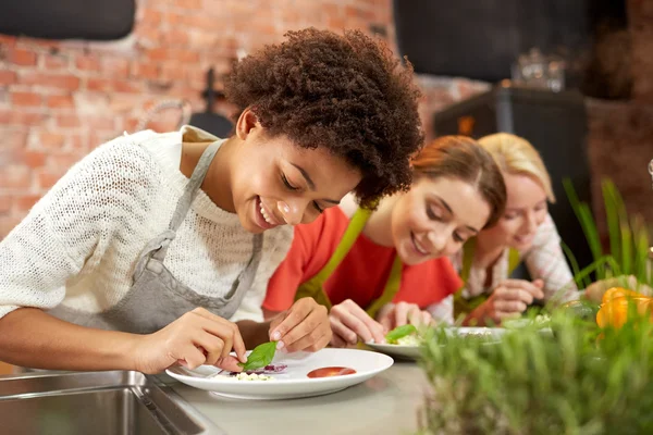 Happy women cooking and decorating dishes — Stock Photo, Image
