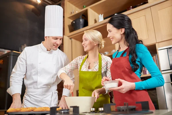 Ευτυχισμένος γυναίκες και σεφ μαγειρεύουν ψήσιμο στην κουζίνα — Φωτογραφία Αρχείου