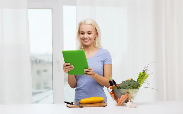 Smiling young woman with tablet pc cooking at home — Stock Photo, Image