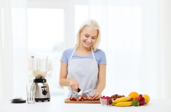 Leende kvinna med blender förbereder skaka hemma — Stockfoto