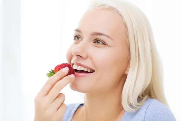 Femme heureuse mangeant des fraises à la maison — Photo