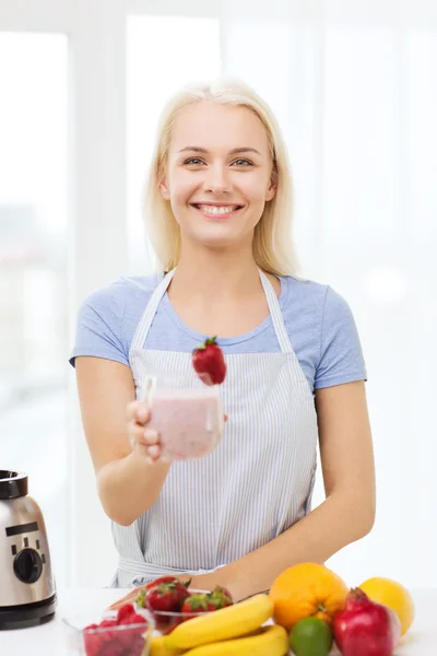 Mulher sorridente segurando vidro de fruto agitar em casa — Fotografia de Stock