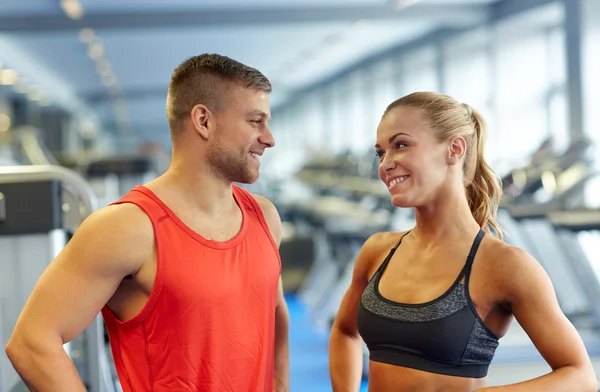 Glimlachende man en vrouw praten in de sportschool — Stockfoto