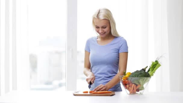 Sorrindo jovem mulher cortando legumes em casa — Vídeo de Stock